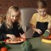 Two kids having fun preparing a healthy meal with fresh ingredients indoors.