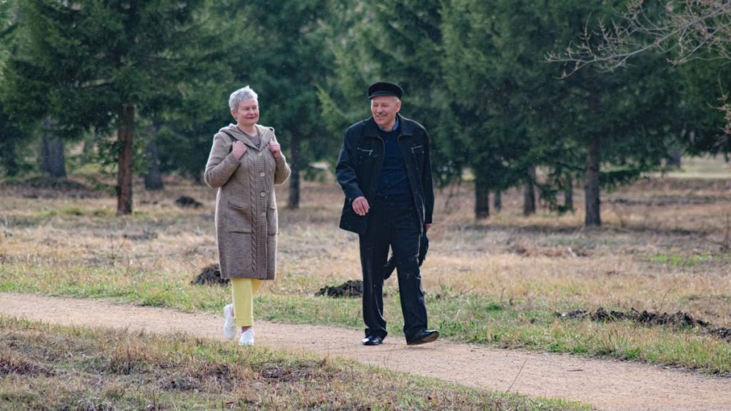 Happy senior couple strolling along a park path on a pleasant spring day.